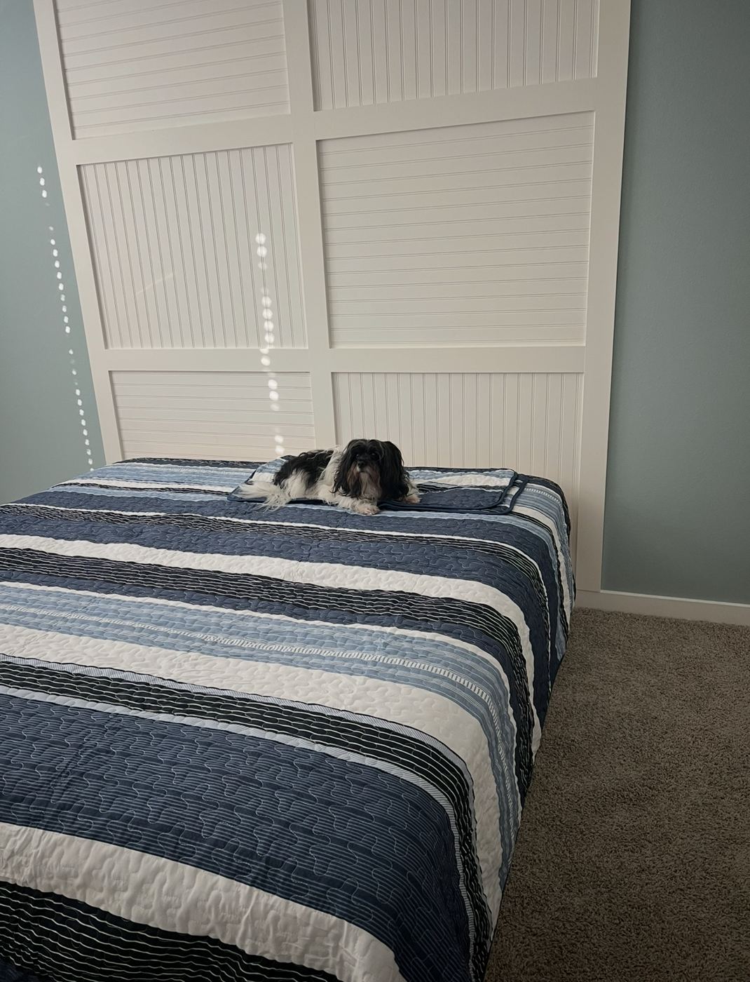 Finished white beadboard feature wall behind a bed
