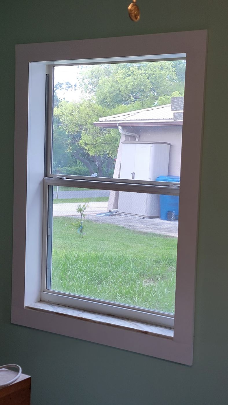 Window with new wide white casing against freshly painted green walls